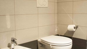 A modern bathroom with a bidet, toilet, and a towel rack.