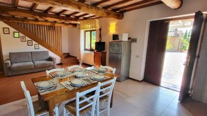 A dining area with a wooden table set for four, a sofa, and a staircase leading to another level. - Tenuta Colombaio  (Casole d'Elsa)