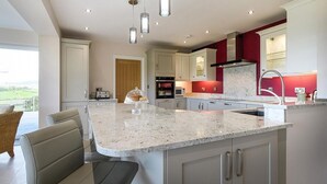 A modern kitchen with a large island, pendant lighting, and a view of the outdoors.