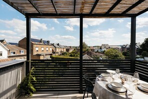 A terrace with a table set for dining, overlooking a residential area with houses and greenery. - The Edgewater Suites - Skyline (Namur)