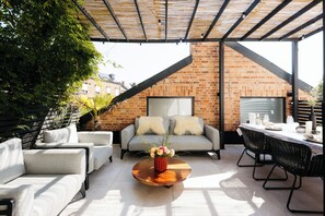 A modern outdoor patio with a brick wall, a wooden table, and a sofa set.