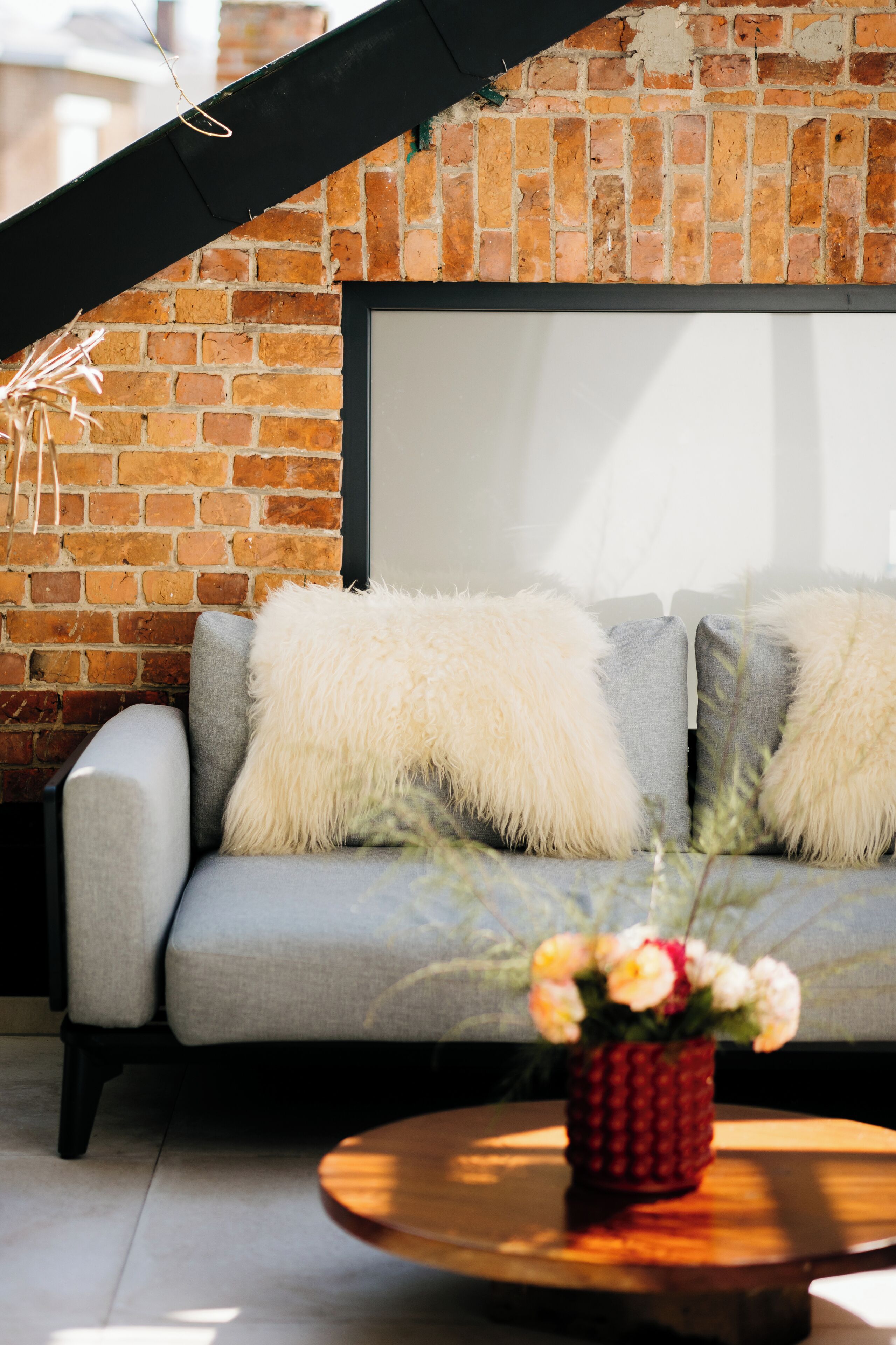 A modern living room with a grey sofa, fluffy white cushions, and a wooden coffee table.