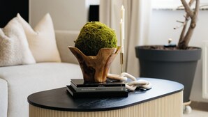 A modern living room with a round, textured coffee table, a potted plant, and a candle. - The Edgewater Suites - Park View (Namur)