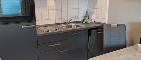 Eine moderne Küche mit dunklen Schränken, einem eingebauten Backofen und einem Spülbecken.