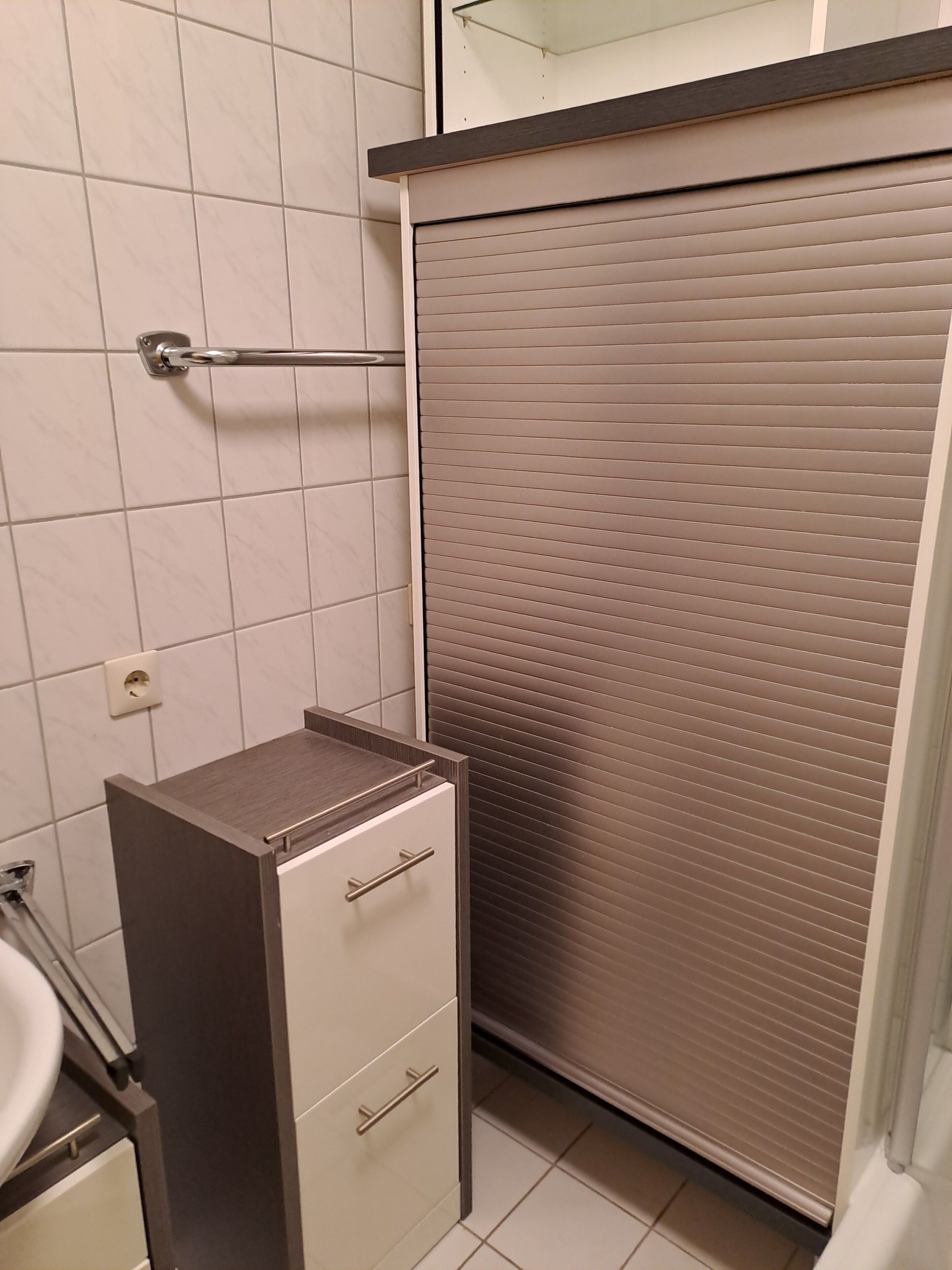 Un baño con inodoro, lavamanos, espejo y toallero.