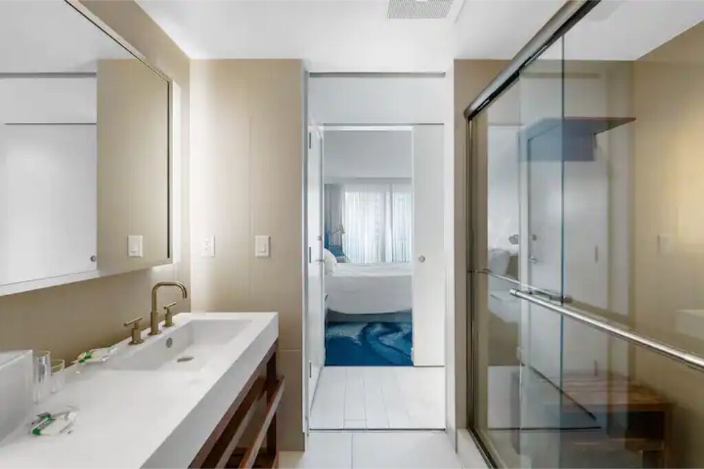 Un baño moderno con un lavamanos grande, espejo y cabina de ducha de vidrio.