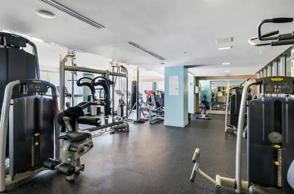 Une salle de sport équipée de divers appareils d’entraînement, notamment des appareils de musculation avec poids et des appareils de cardio.