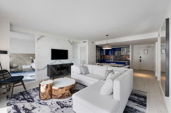 A modern living room with a white sofa, a round coffee table, and a TV mounted on the wall. - The Luxurious W hotel Residence Beachfront Condo Oasis (Fort Lauderdale)