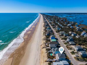 Vista aérea de una zona residencial costera con casas a lo largo de la playa y una carretera que discurre paralela a la orilla.