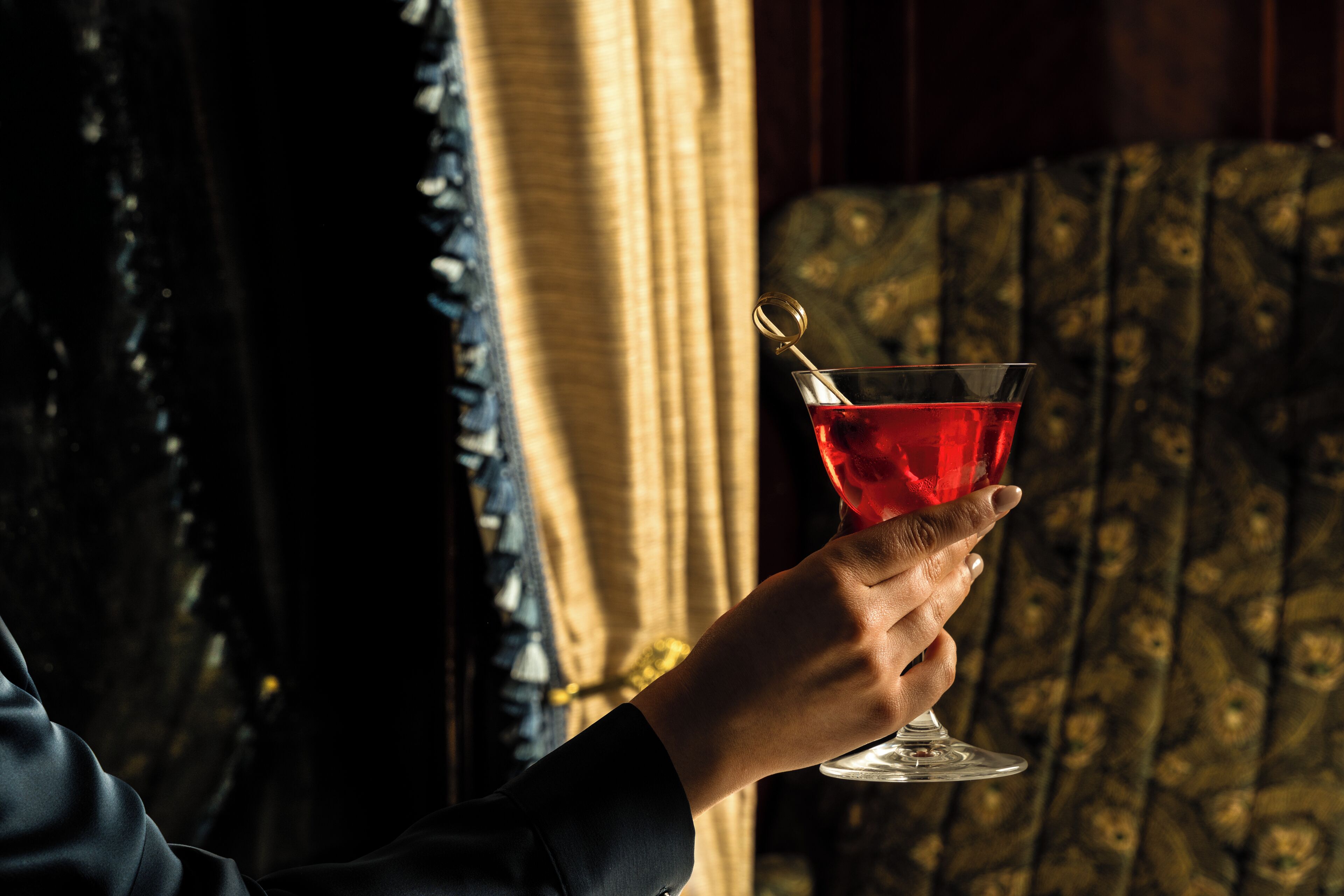 Une personne tenant un verre à martini avec une paille dorée.