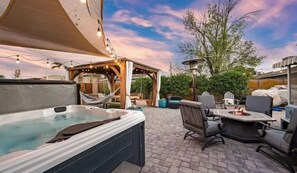 Une terrasse extérieure dotée d’un jacuzzi, d’un espace salon et d’une pergola.