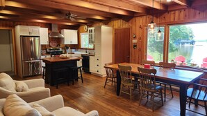A spacious kitchen with wooden cabinets, a stainless steel refrigerator, and a dining area with a wooden table and chairs.