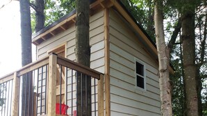 A treehouse with a wooden deck and a small window.
