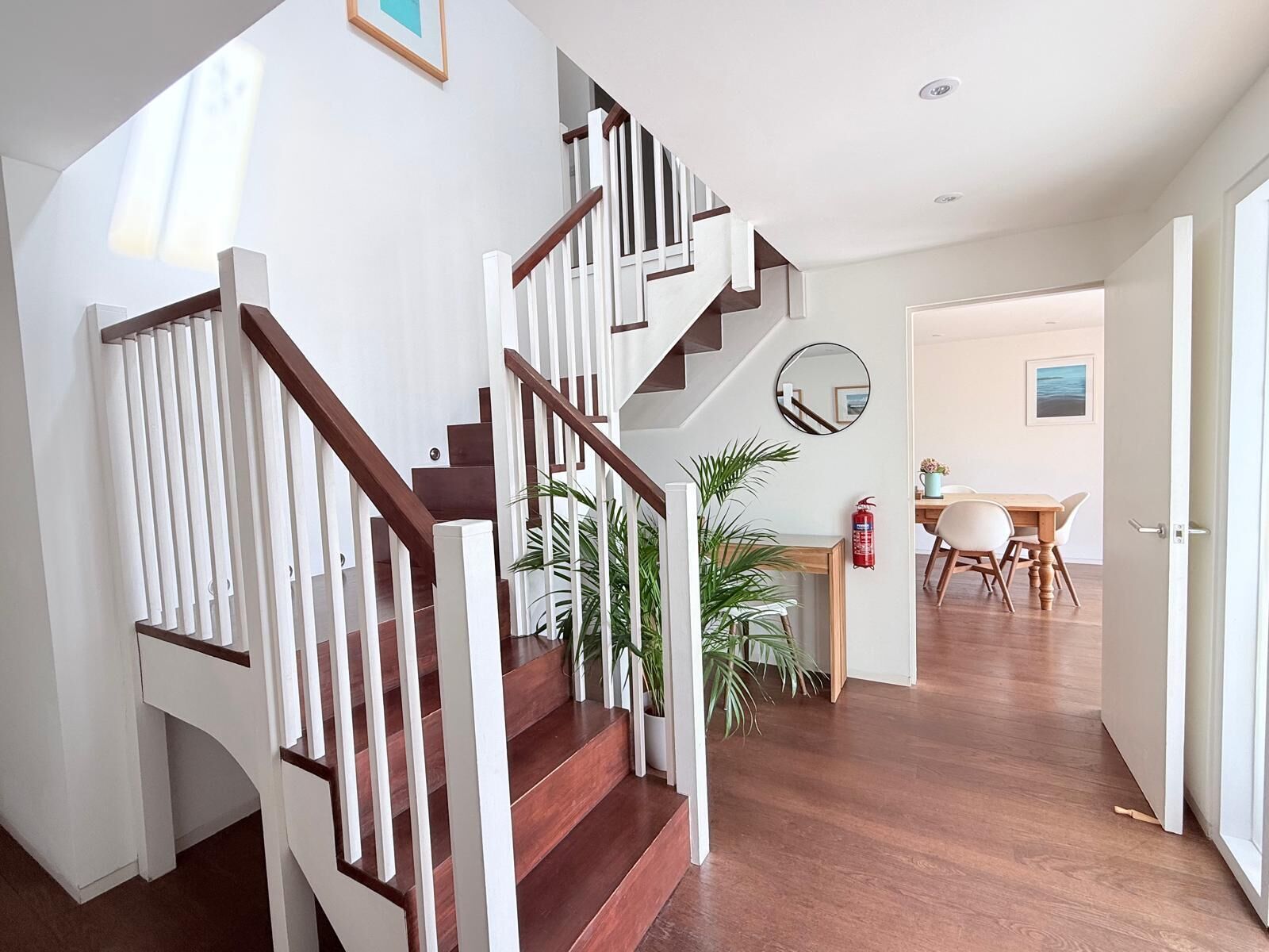 A staircase with white railings and wooden steps leading to a dining area with a table and chairs.