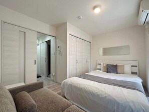 Une chambre d’hôtel moderne équipée de deux lits, d’un canapé, d’une armoire et d’un miroir.