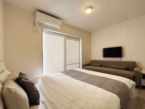 Une chambre d’hôtel équipée d’un lit, d’un canapé, d’une télévision et d’un appareil de climatisation.