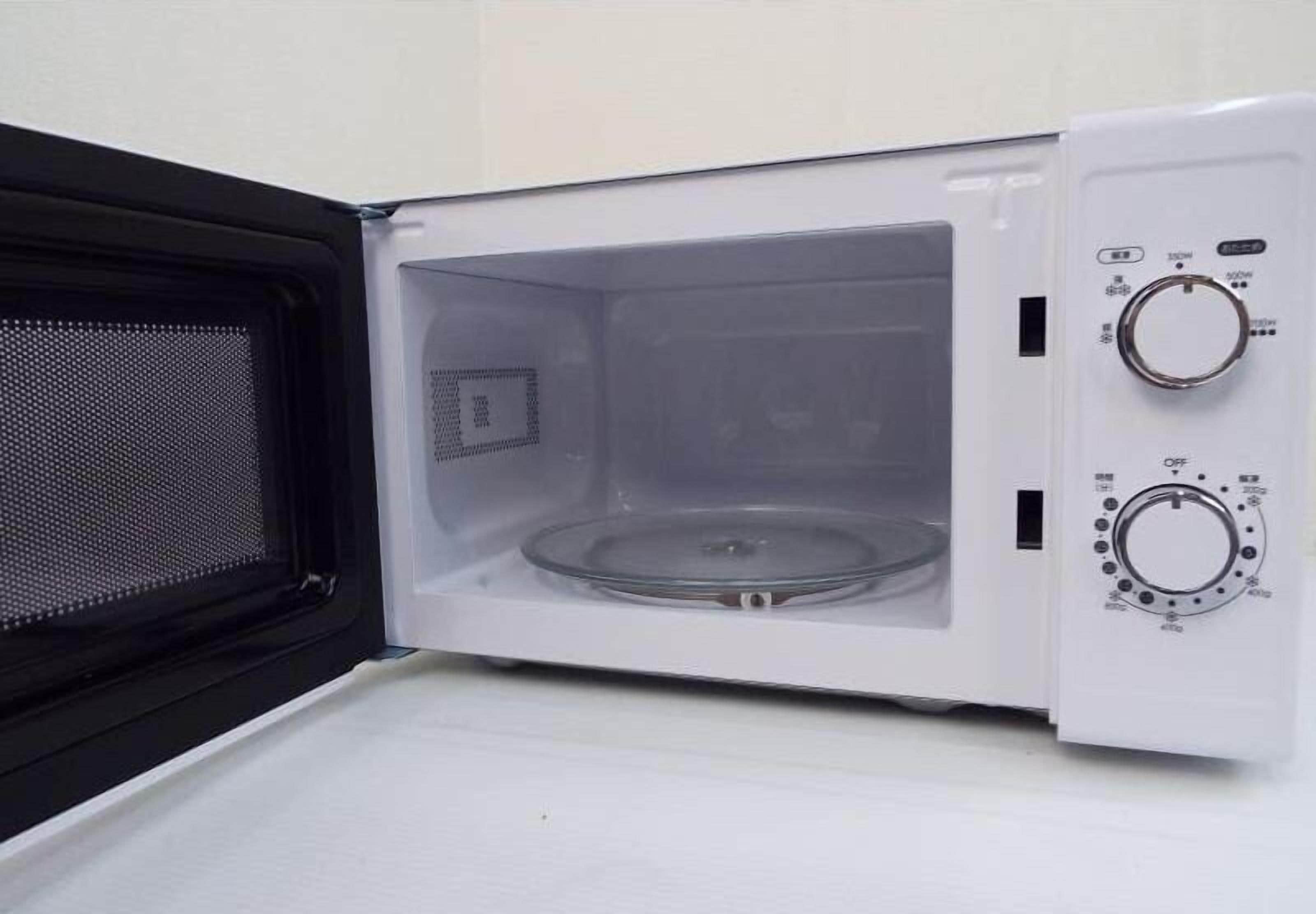Um micro-ondas vazio, com botões de controle e porta de malha.