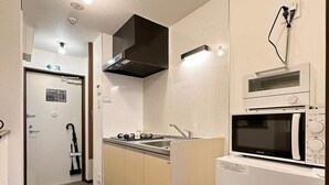 Una cocina compacta con microondas, horno y estufa. Cuenta con un lavamanos pequeño y un armario.