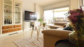 Ein Wohnzimmer mit Fernseher, einer Couch, einem kleinen Tisch und einer Vitrine.