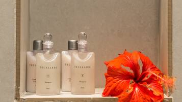 A shelf with three bottles of Trussardi shampoo and a red flower.