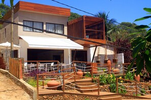 A modern house with a covered patio, outdoor seating, and a garden area with potted plants and a wooden deck.