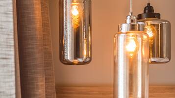 A modern interior with pendant lights, a wooden panel wall, a power outlet, and a vase with flowers.
