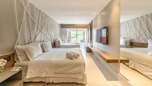 A modern hotel room with a large bed, a bedside table, a TV, and a view of the outdoors.