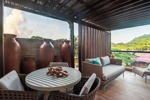 A covered patio with wicker furniture, a round table with pretzels, and terracotta pots. - Pousada Corveta (Fernando de Noronha)