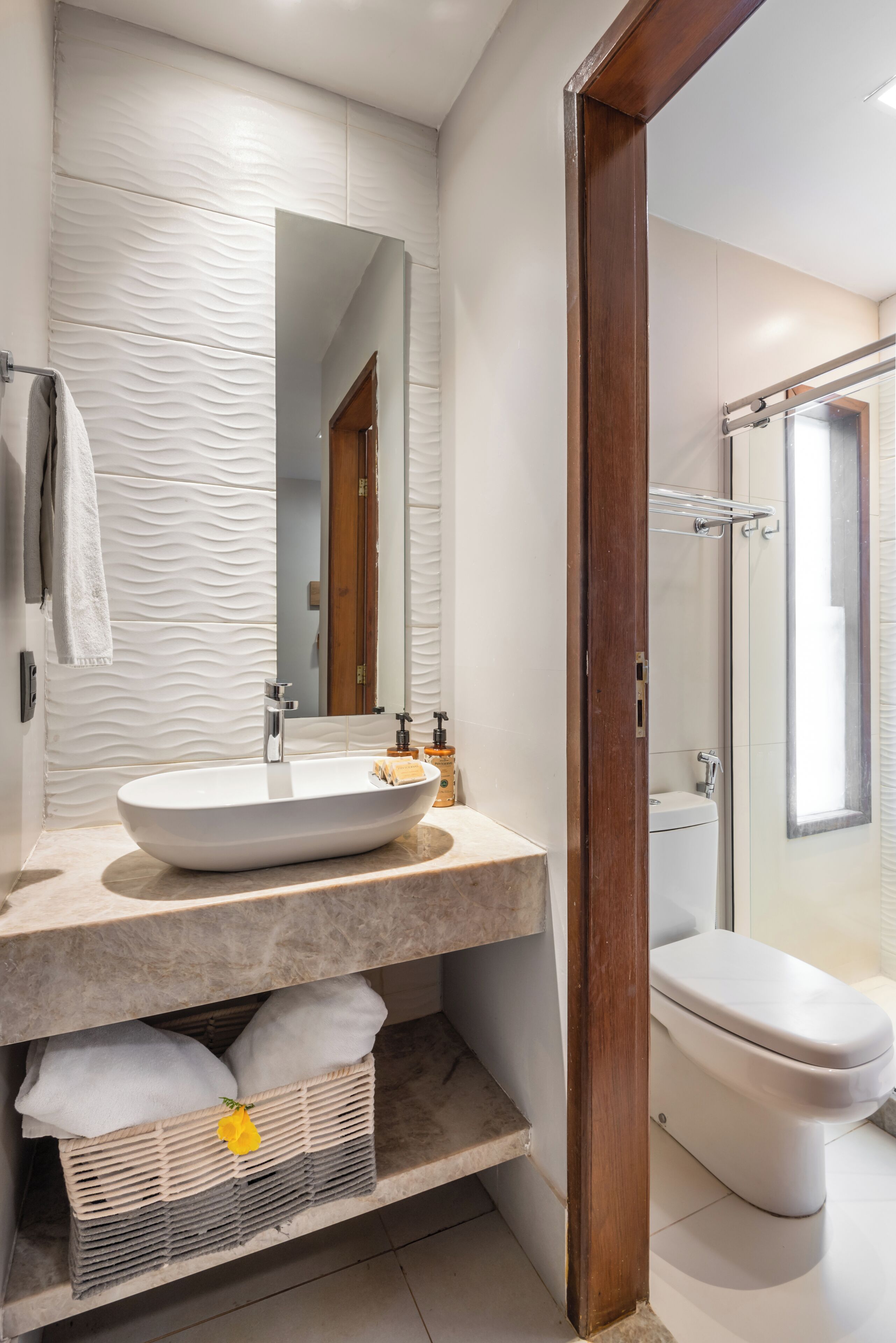 A modern bathroom with a large oval sink, a mirror, a shower, and a toilet.