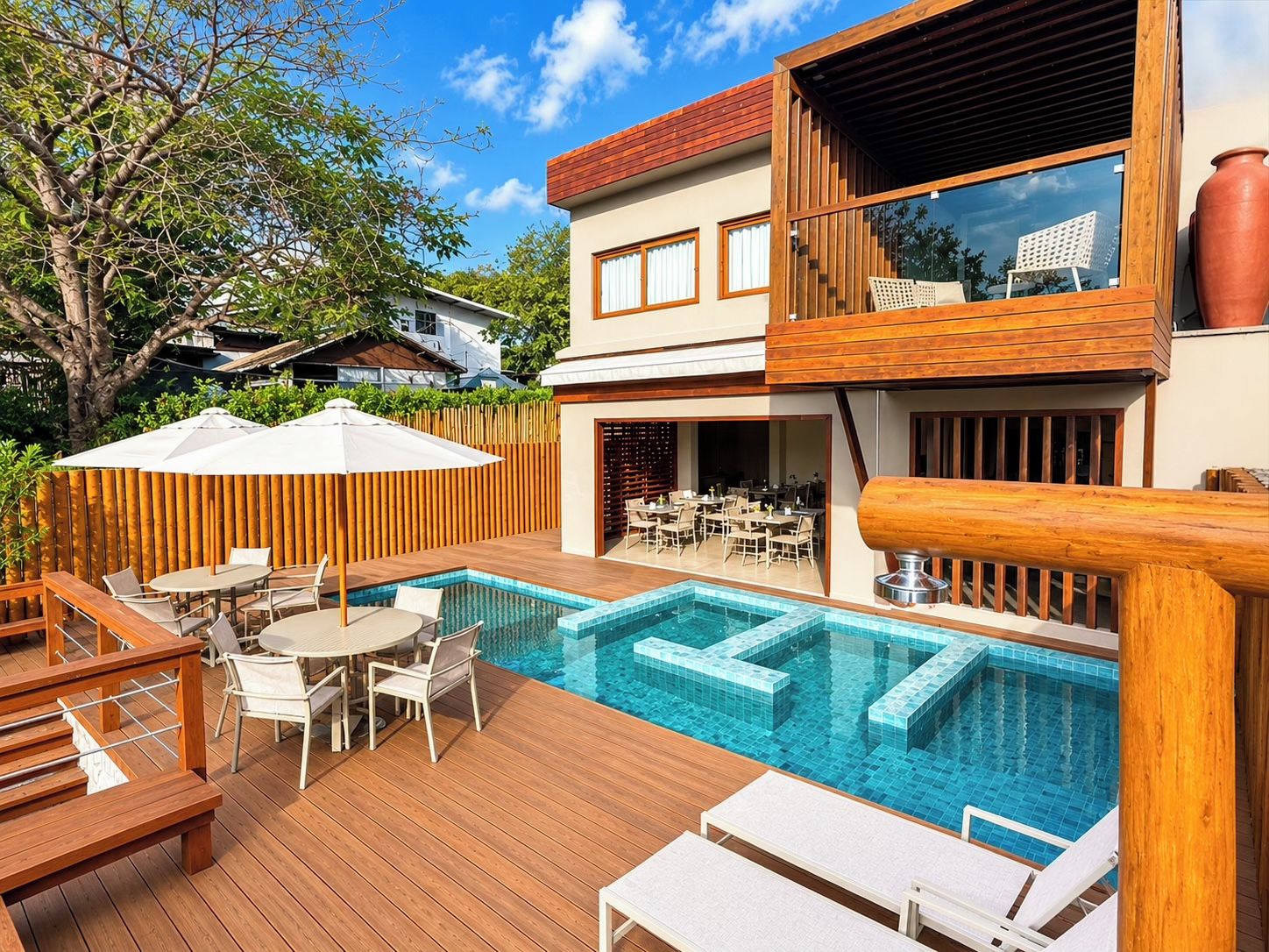 A modern outdoor pool area with wooden deck, lounge chairs, and a dining area.