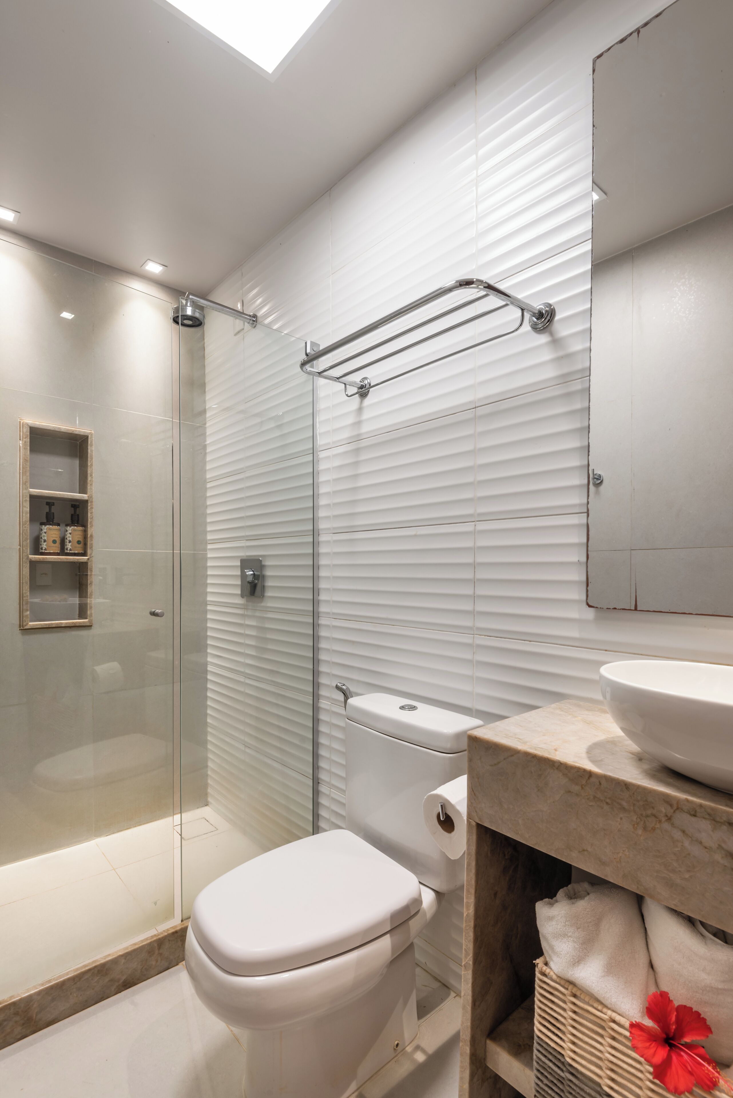 A modern bathroom with a glass shower enclosure, a toilet, and a vanity with a sink and mirror.