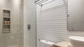 A modern bathroom with a glass shower enclosure, a toilet, and a vanity with a sink and mirror.