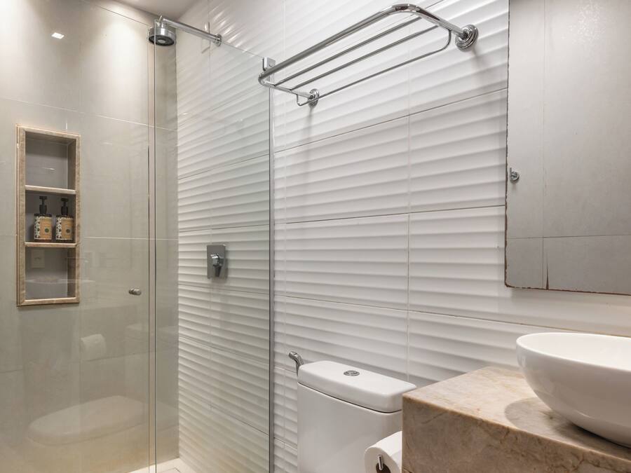 A modern bathroom with a glass shower enclosure, a toilet, and a vanity with a sink and mirror.