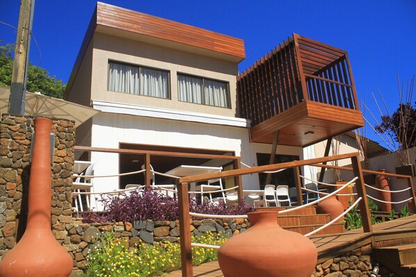 A modern two-story house with a stone facade, large windows, and a wooden deck.