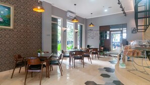 A cafe with wooden tables and chairs, a menu on the wall, and a staircase to the right. - OYO 3216 Ellegan Residence (South Tangerang)