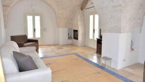 Un vaste espace de vie doté d’un haut plafond en arc de cercle, d’un canapé blanc, d’un fauteuil marron et d’une petite table.