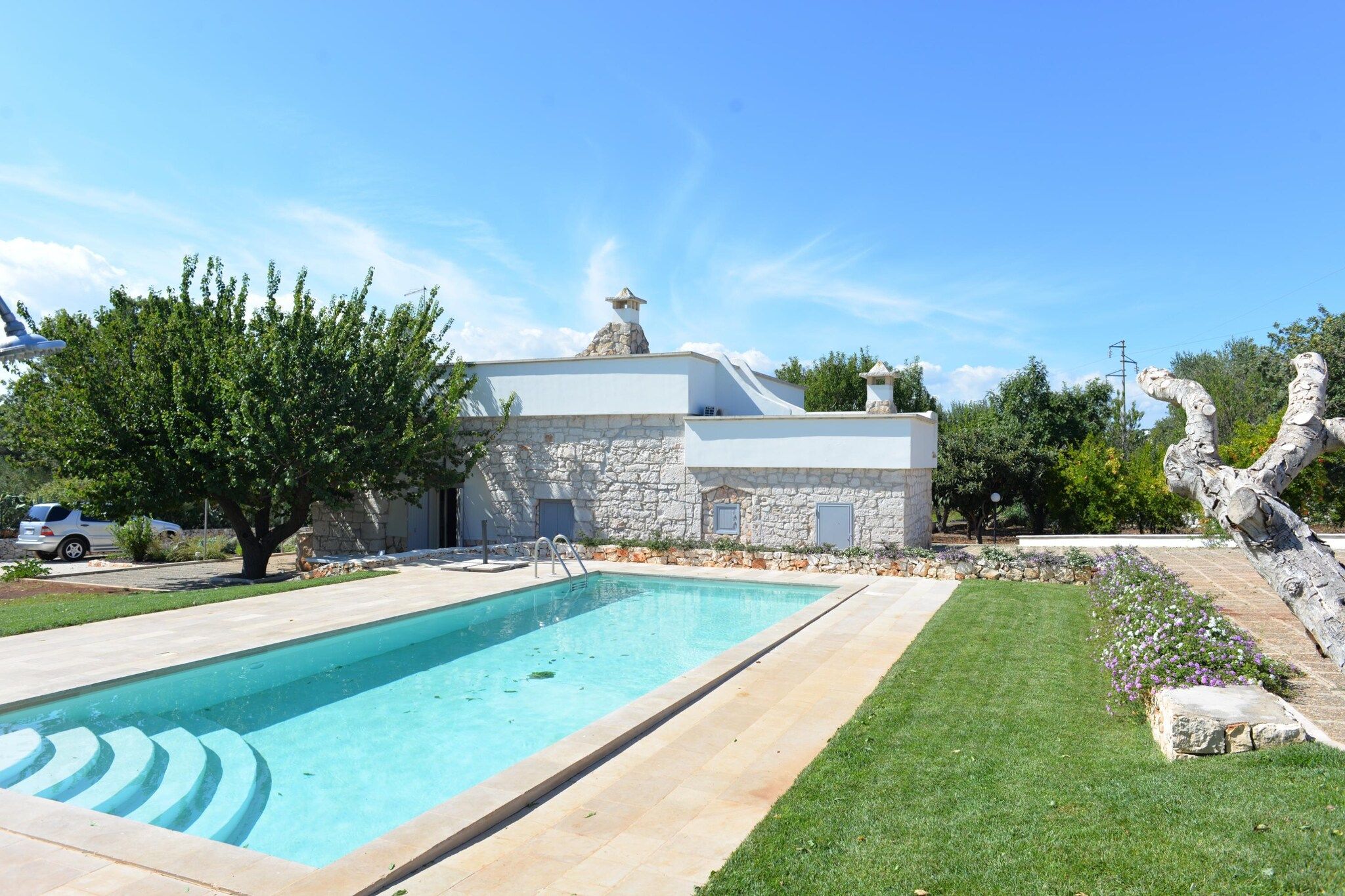 Ein Wohnhaus mit Schwimmbad, Steinaußenwand und gepflegtem Rasen.