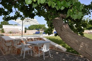 An outdoor patio with a stone wall, a table, and chairs.