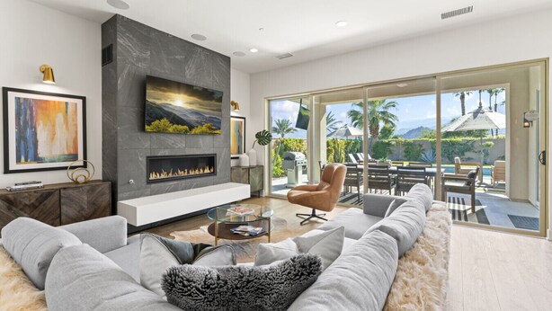 Una sala de estar moderna con chimenea, un sofá grande y una mesa de centro de vidrio.