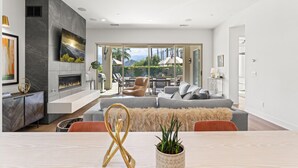 Una sala de estar moderna con chimenea, un sofá grande y un comedor con mesa y sillas.