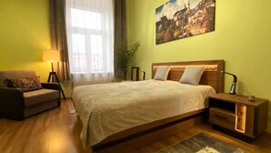 Une chambre à coucher avec un grand lit, une table de chevet, une lampe, une chaise et une fenêtre avec des rideaux.