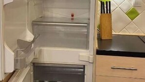 Une cuisine équipée d’un réfrigérateur encastré, d’un plan de travail en bois et d’un crédence carrelée.