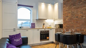 Een moderne keuken met witte kastjes, een bakstenen muur en een eetgedeelte met zwarte stoelen en een tafel gedekt voor vier personen.