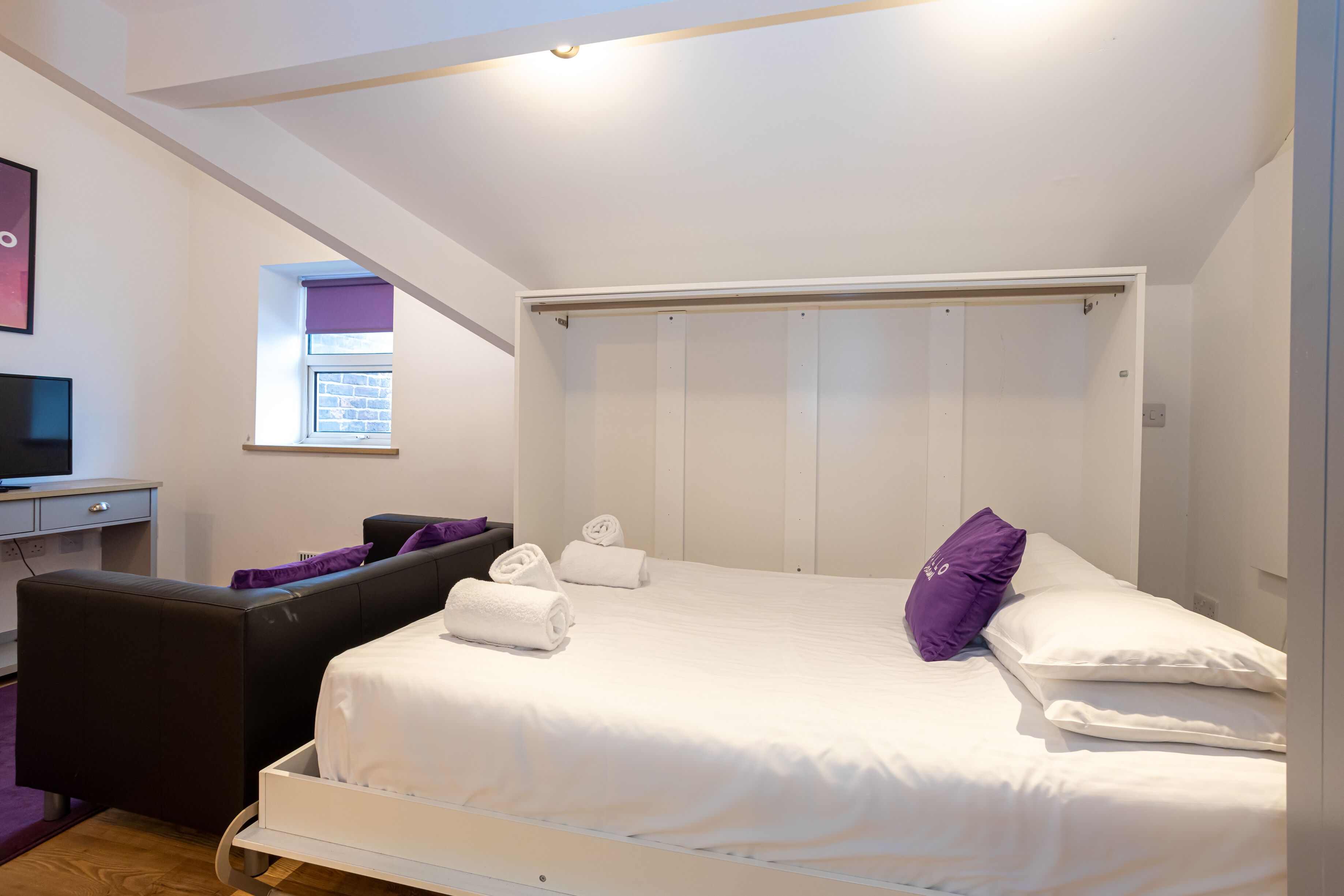 A modern bedroom with a bed, a desk, and a chair.