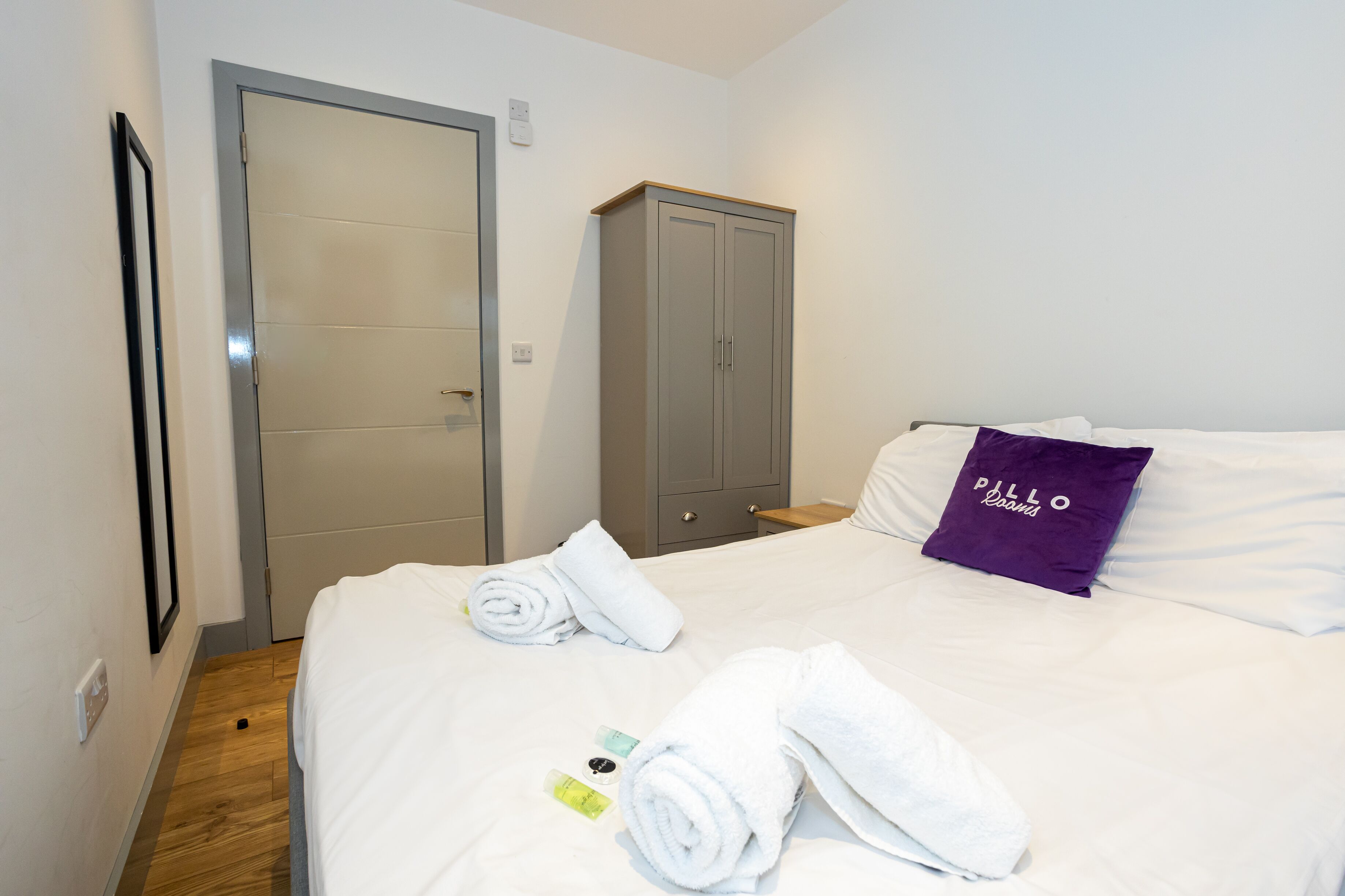 Una habitación de hotel con una cama, un armario y una puerta.