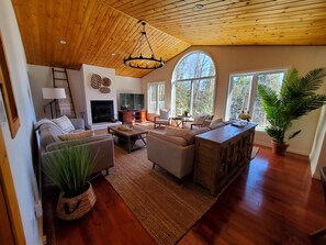 Amplia sala de estar con chimenea, asientos cómodos y ventanas grandes que ofrecen luz natural.
