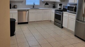 A modern kitchen with white cabinets, a stainless steel dishwasher, an oven, a microwave, and a refrigerator. - Upscale & Elevated - 3BR 2BA (Newark)