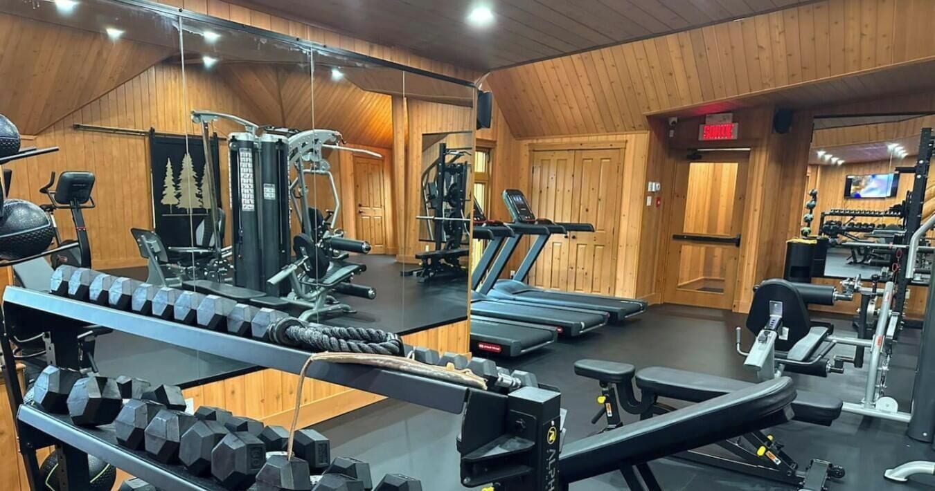 Un gimnasio con cintas de correr, máquinas de pesas y pesas sueltas.