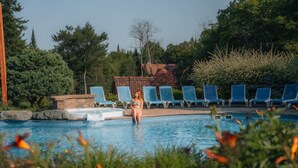 En swimmingpool med solstolar och en person som sitter vid poolen.