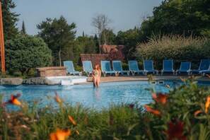 Una piscina amb gandules i una persona asseguda al costat.